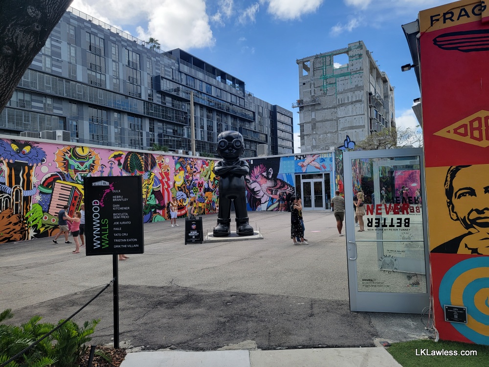 Photo from entrance to Wynwood Walls with assorted painting and a large statue in the middle